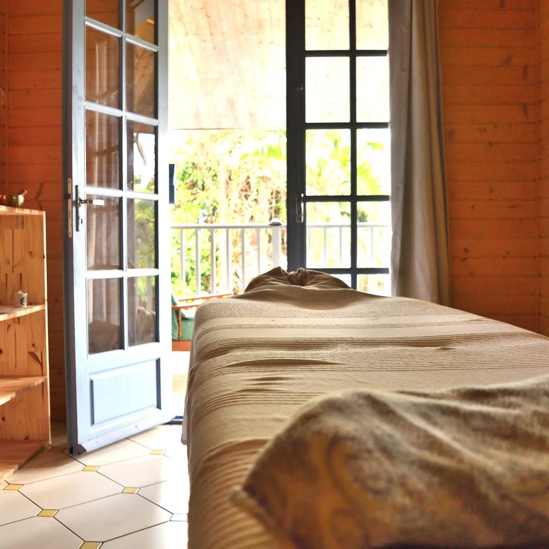 Table de massage dans la salle en bois de L'Eden des Sens, porte ouverte sur le jardin